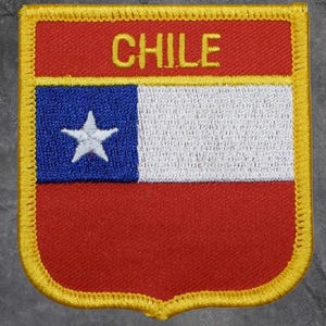 May include: Embroidered patch featuring the flag of Chile. The design includes a blue square with a white star, a white stripe, and a red background. The word "CHILE" is embroidered in yellow at the top, with a yellow border.
