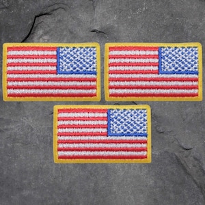 Könnte beinhalten: Drei gestickte amerikanische Flaggen-Patches mit gelbem Rand. Die Flaggen sind rot, weiß und blau.