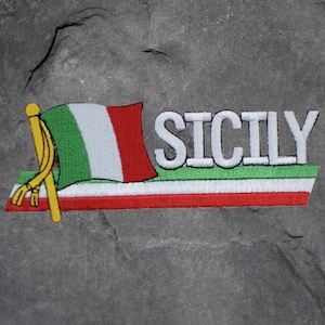 May include: Embroidered patch featuring the word "SICILY" in white, with a green, white, and red flag design. The flag is on a yellow pole with a gold tassel. The patch has a red, white, and green border.