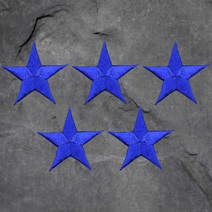 May include: Five blue embroidered star patches on a gray stone background.