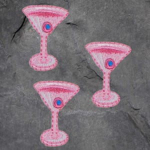 May include: Three pink embroidered martini glass patches with blue centers.