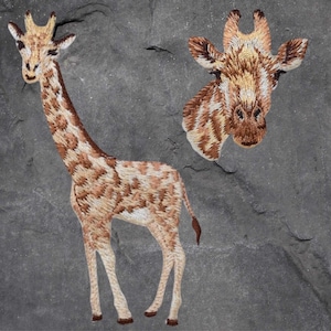 以下が含まれることがあります： キリンの刺繍パッチが2つ。1つは全身、もう1つは頭部のアップ。キリンは茶色とベージュで、背景は白です。