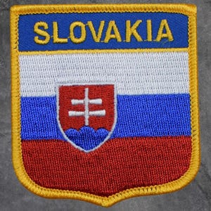 May include: Embroidered patch depicting the flag of Slovakia. The patch features a blue top with the word "SLOVAKIA" in yellow, a white centre, and a red bottom. A coat of arms is in the centre. The patch is bordered with gold.