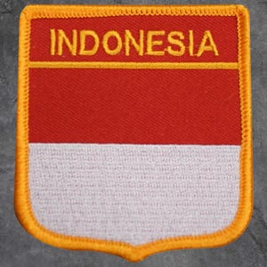 May include: A rectangular patch featuring the word "INDONESIA" in gold lettering above a red and white Indonesian flag design. The patch has a gold border with a decorative edge.