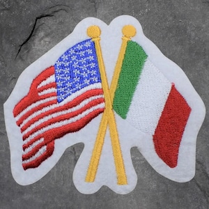 May include: Embroidered patch featuring the American and Italian flags crossed. The American flag has red and white stripes with blue stars. The Italian flag has green, white, and red vertical stripes. The flags are on gold poles.
