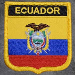May include: Embroidered patch featuring the flag of Ecuador. The patch has a yellow upper section, a blue middle section, and a red lower section. The text "ECUADOR" is displayed in yellow on a black background. The patch also includes the Ecuadorian coat of arms.