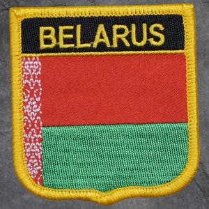 May include: Embroidered patch featuring the flag of Belarus. The patch has a black border with the word "BELARUS" in yellow. The flag design includes red and green horizontal stripes with a white and red vertical pattern on the left.