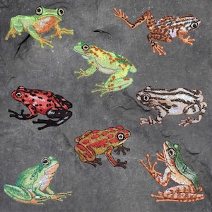 May include: A collection of eight embroidered frog patches in various colors and patterns, including green, red, brown, and black. The patches are all different sizes and shapes, and they are all stitched with intricate details.