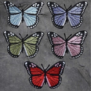 May include: Five embroidered butterfly patches in various colors, including blue, purple, green, pink, and red. The patches are all the same size and shape, and they have a black outline.