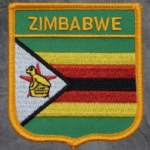 Könnte beinhalten: Gestickter Aufnäher mit der Flagge von Simbabwe. Der Aufnäher hat einen grünen oberen Abschnitt mit dem Wort "ZIMBABWE" in Gold. Darunter befinden sich horizontale Streifen in Gelb, Rot, Schwarz und Gelb. Ein weißes Dreieck enthält einen gelben Vogel und einen roten Stern.