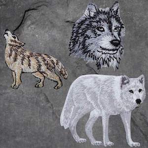 May include: Three embroidered iron-on patches of wolves. The first wolf is brown and white with a tan stripe down its back. The second wolf is white with a gray head and black eyes. The third wolf is white with a gray head and black eyes.