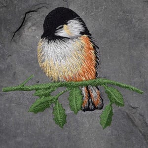 May include: Embroidered image of a chickadee bird perched on a green branch with leaves. The bird has a black head, white cheeks, and orange and grey body. The background is a textured grey.