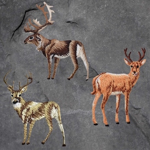May include: Three embroidered patches of different types of deer. The patches are brown and white and are on a grey background.