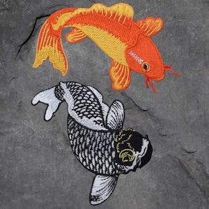 May include: Two embroidered koi carp patches. One is orange and yellow, the other is black and white. The patches feature detailed stitching, showing the scales and fins of the fish. The patches are designed for decorative use.