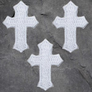 May include: Three white iron-on patches in the shape of a cross. The crosses have a slightly textured surface.