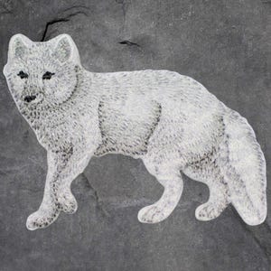 May include: A white arctic fox figurine with black eyes and a textured fur design. The fox is depicted in a walking pose against a dark gray background, showcasing its detailed features.