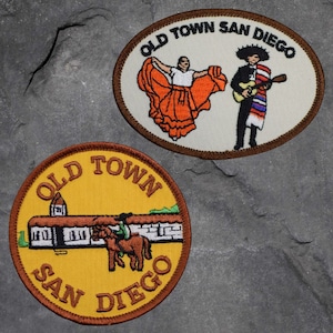 May include: Two embroidered patches with the text "Old Town San Diego". One patch features a couple dancing in traditional clothing, the other patch features a building with a horse and rider.