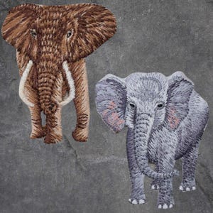 Könnte beinhalten: Zwei gestickte Elefanten-Patches. Der größere Elefant ist braun mit weißen Stoßzähnen und der kleinere Elefant ist grau mit rosa Ohren.