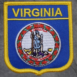Könnte beinhalten: Gestickter Aufnäher mit dem Wort "VIRGINIA" in gelben Blockbuchstaben auf blauem Hintergrund. Der Aufnäher hat einen gelben Rand und zeigt das Siegel des Staates Virginia.