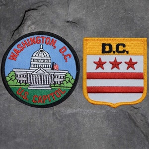 May include: Two embroidered patches featuring Washington, D.C. imagery. One is circular, depicting the U.S. Capitol building with text "WASHINGTON, D.C." and "U.S. CAPITOL." The other is shield-shaped, with "D.C." and three red stars.