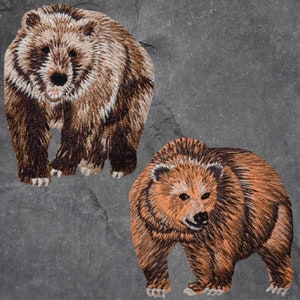 May include: Two brown bears, one standing and one walking, are embroidered on a grey background. The bears are facing the viewer and have brown fur with lighter brown accents.