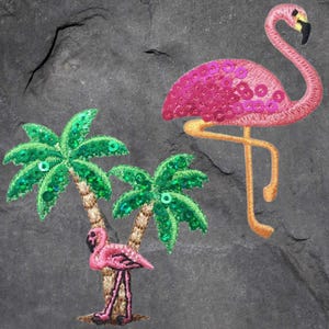 Peut inclure: Deux patchs brodés de flamants roses avec des paillettes, l'un debout sur une seule patte et l'autre debout sur les deux pattes. Il y a deux patchs de palmiers verts avec des paillettes.