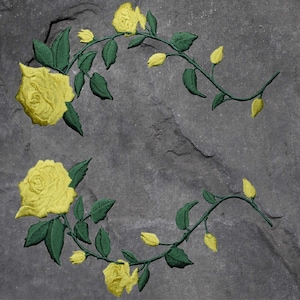 May include: A gray stone background with two yellow rose vines with green leaves. The vines are intertwined and form a circle.