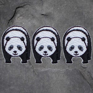 May include: Three black and white panda bear iron-on patches. The patches are embroidered and have a black outline.