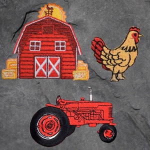 May include: Embroidered patches depicting a red barn with hay bales, a yellow and brown chicken, and a red tractor. The barn has white details and the tractor has black tyres. The patches are on a grey background.