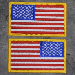 May include: Two embroidered American flag patches with yellow stitching around the edges. The top patch has the stars on the left side and the bottom patch has the stars on the right side.