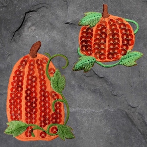 May include: Two embroidered pumpkin patches with green leaves and orange sequins. The pumpkins are sewn with a detailed design.