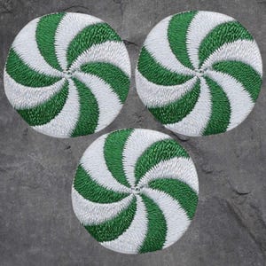 May include: Three green and white peppermint swirl candy cane shaped patches. The patches are embroidered with white thread on a green fabric.
