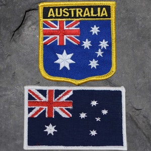 May include: Two embroidered patches featuring the Australian flag. The top patch is a shield shape with the word "AUSTRALIA" in yellow letters on a black background. The bottom patch is a rectangular shape.
