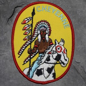May include: Embroidered patch with a yellow background and a red border. The patch features a Native American chief on horseback, holding a spear. The word "CHEYENNE" is arched across the top in light blue.