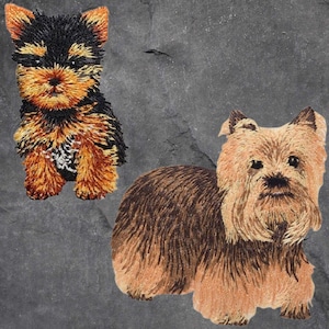 May include: Two embroidered patches of Yorkshire Terriers. One is sitting, the other is standing. Both patches feature black, brown, and tan colors, with detailed stitching to depict the dogs' fur and features. The patches are likely for clothing or accessories.