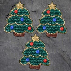 May include: Three green felt Christmas tree ornaments with gold trim, red and blue felt ornaments, and a gold star on top.