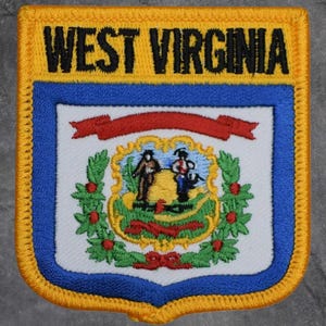 Könnte beinhalten: Gestickter Aufnäher mit dem Schriftzug "WEST VIRGINIA" in Schwarz auf gelbem Grund. Der Aufnäher hat einen blauen Rand und ein zentrales Emblem mit Figuren und dem Staatssiegel. Rechteckig mit abgerundeten Ecken.
