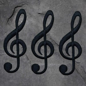 May include: Three black treble clef symbols against a textured gray background. The musical notes are detailed with a woven or textured appearance, creating a contrast with the stone-like backdrop. The design is simple yet striking.