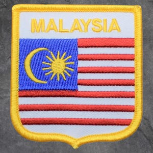 May include: Embroidered patch featuring the flag of Malaysia. The patch has a white background with the word "MALAYSIA" in gold letters. The flag design includes a blue square with a yellow crescent and star, and red and white stripes.