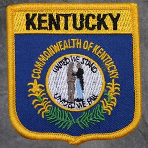 May include: A rectangular patch with a yellow border and the word "KENTUCKY" in black letters across the top. The patch features a blue background with the state seal, including the text "COMMONWEALTH OF KENTUCKY".