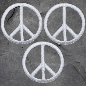May include: Three white peace sign patches on a gray background.