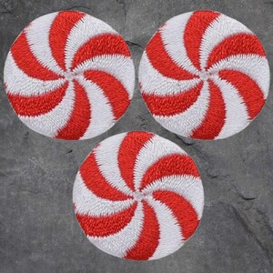 May include: Three red and white peppermint candy swirl iron-on patches. The patches are round and have a white background with red swirls.