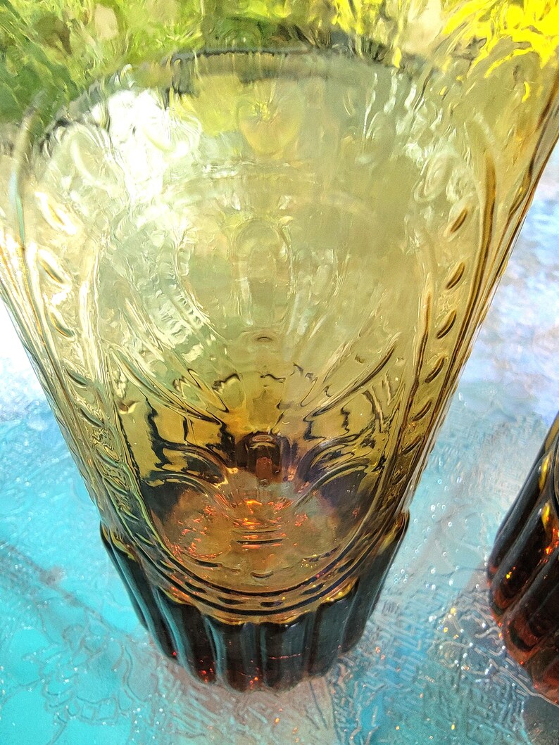 May include: Two amber glass vases with a textured, embossed design. The vases have a flared top and a ribbed base.
