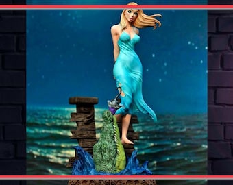 Pode incluir: Estatueta de uma mulher em um vestido turquesa esvoaçante, em pé sobre uma estrutura de madeira acima de um crocodilo. A cena é ambientada em um fundo azul escuro com estrelas. A estatueta tem cabelo loiro e segura uma pequena criatura.