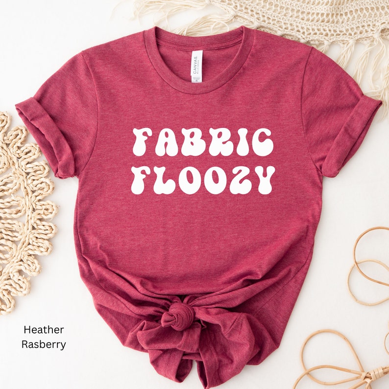 Pu&ograve; includere: T-shirt color lampone con la scritta bianca "FABRIC FLOOZY" in un font retr&ograve;. Le maniche sono arrotolate e la maglietta &egrave; annodata in vita. La parola "Canvas" &egrave; stampata sull'etichetta.