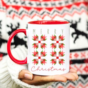 May include: White ceramic mug with a red interior and handle. The mug features a festive design of red and green geometric shapes and the words "MERRY Christmas" in green and red script.