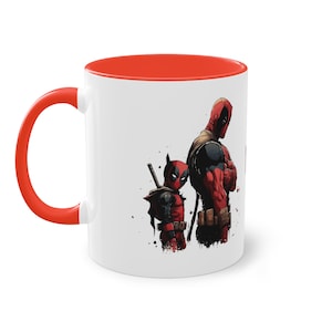 Può includere: Una tazza da caffè bianca con interno rosso e una grafica di due personaggi di Deadpool. Il Deadpool più grande è in piedi con le braccia incrociate, mentre il Deadpool più piccolo è in piedi dietro di lui con una spada.