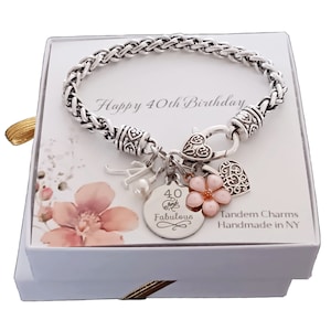 May include: A silver bracelet with a charm that says "40 Fabulous" and other charms, including a flower, a heart, and a letter A. The bracelet is in a white box with the words "Happy 40th Birthday" and "Tandem Charms Handmade in NY".