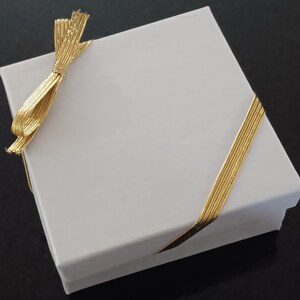 white gift box with gold elastic stretch ribbon and bow