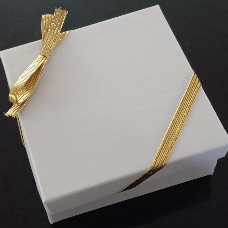 white gift box with gold elastic stretch ribbon and bow